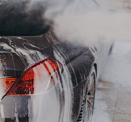 Professional car wash with high pressure washer and cleansing foam outdoors